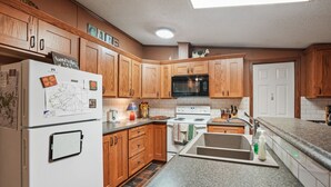 Una cocina con armarios de madera, un refrigerador, un microondas, una estufa y un lavaplatos.