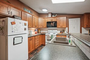 Una cocina con armarios de madera, un refrigerador, un microondas, una estufa y un lavaplatos.