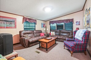 A living room with two brown leather sofas, a plaid armchair, a coffee table, and a television.