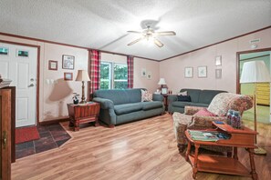 A furnished living room with a ceiling fan, two sofas, a coffee table, and a patterned armchair. - Hocking Hills Majestic Retreats - Nancy's Cabin (Rockbridge)