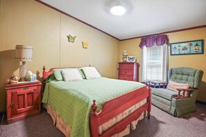 Une chambre à coucher avec un lit, une commode, une chaise et une fenêtre avec des stores.