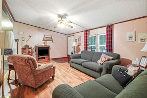 A living room with a green sofa, a patterned armchair, and a wooden floor.