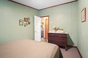 A bedroom with a bed, dresser, and a door leading to a hallway.