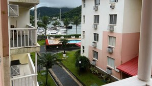 Un hotel con piscina, varios balcones y vistas al mar y a las montañas.