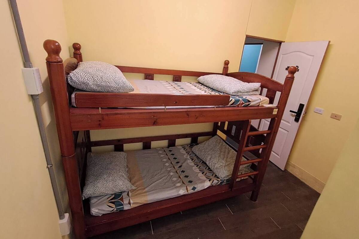 A bunk bed with two levels, a wooden ladder, and patterned bedding.