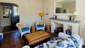 Una sala de estar con chimenea, dos sillones, un sofá y una mesa de centro de madera.