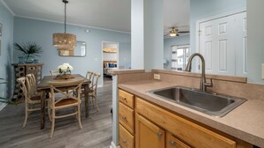 A kitchen with a wooden table, chairs, a sink, and cabinets. - Villages of Five Points 3rd floor condo - great location & amenities! (Lewes)