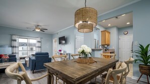 A dining area with a wooden table, wicker chairs, and a hanging light fixture. - Villages of Five Points 3rd floor condo - great location & amenities! (Lewes)