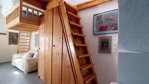 Een kamer met een houten wenteltrap, een witte bank en een bed.