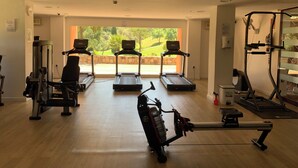 Un gimnasio con cintas de correr, una máquina de remo y equipo de levantamiento de pesas.