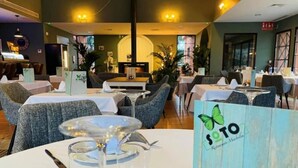 Un interior de restaurante con mesas redondas, sillas y una zona de bar central.