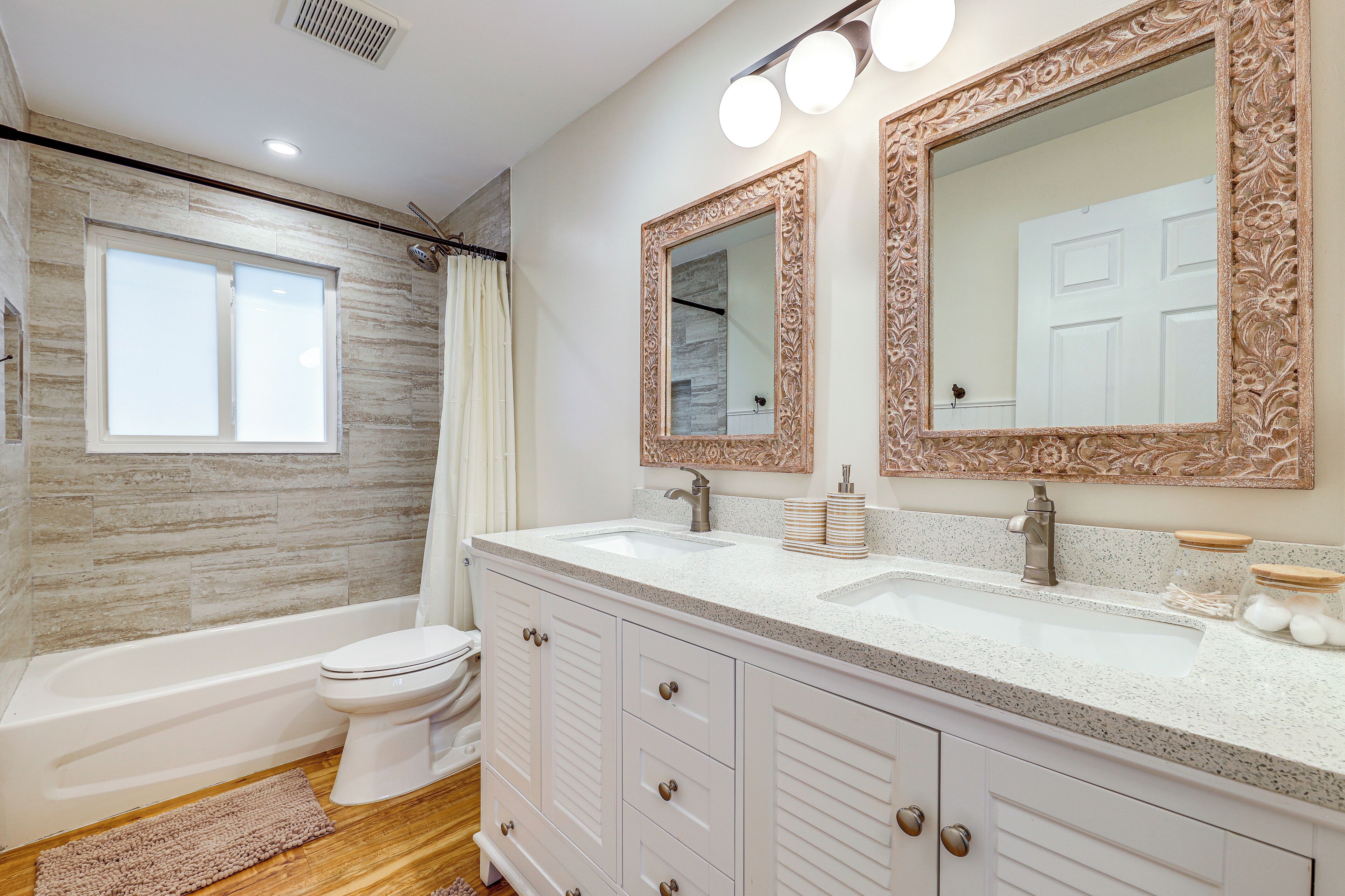 A modern bathroom with a bathtub, toilet, and vanity with two sinks.