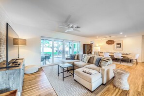A modern living room with a sectional sofa, a coffee table, and a dining area with a table and chairs.