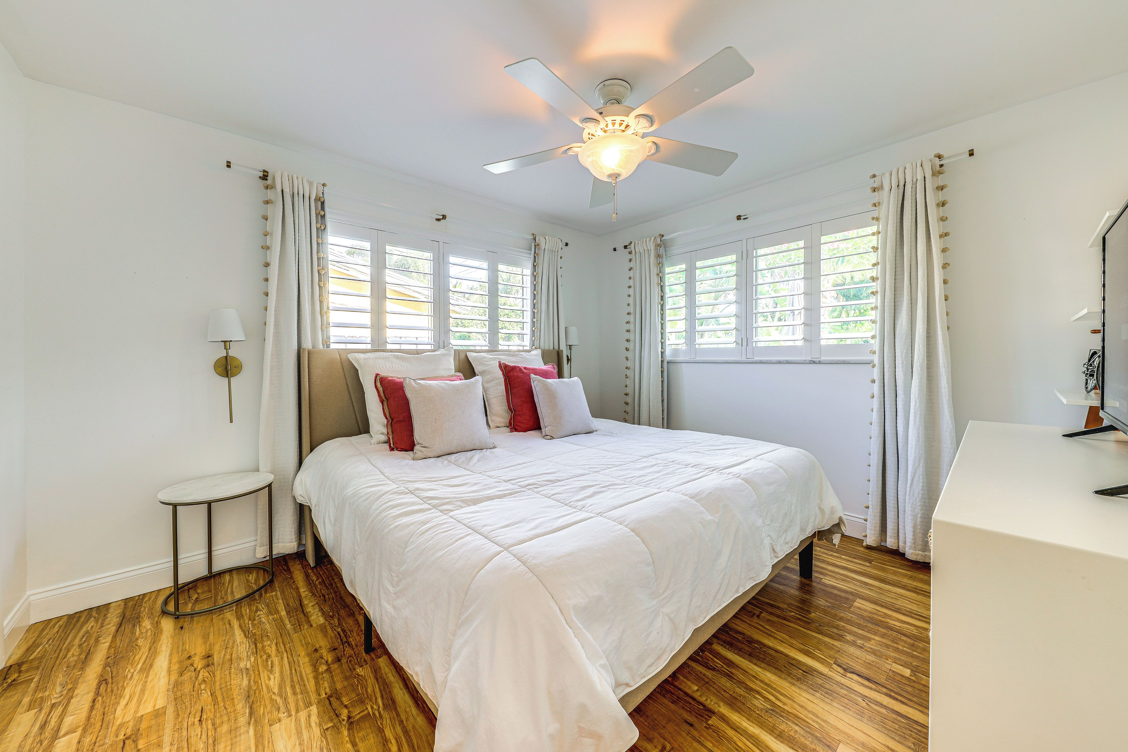 A bedroom with a bed, a ceiling fan, and a desk.