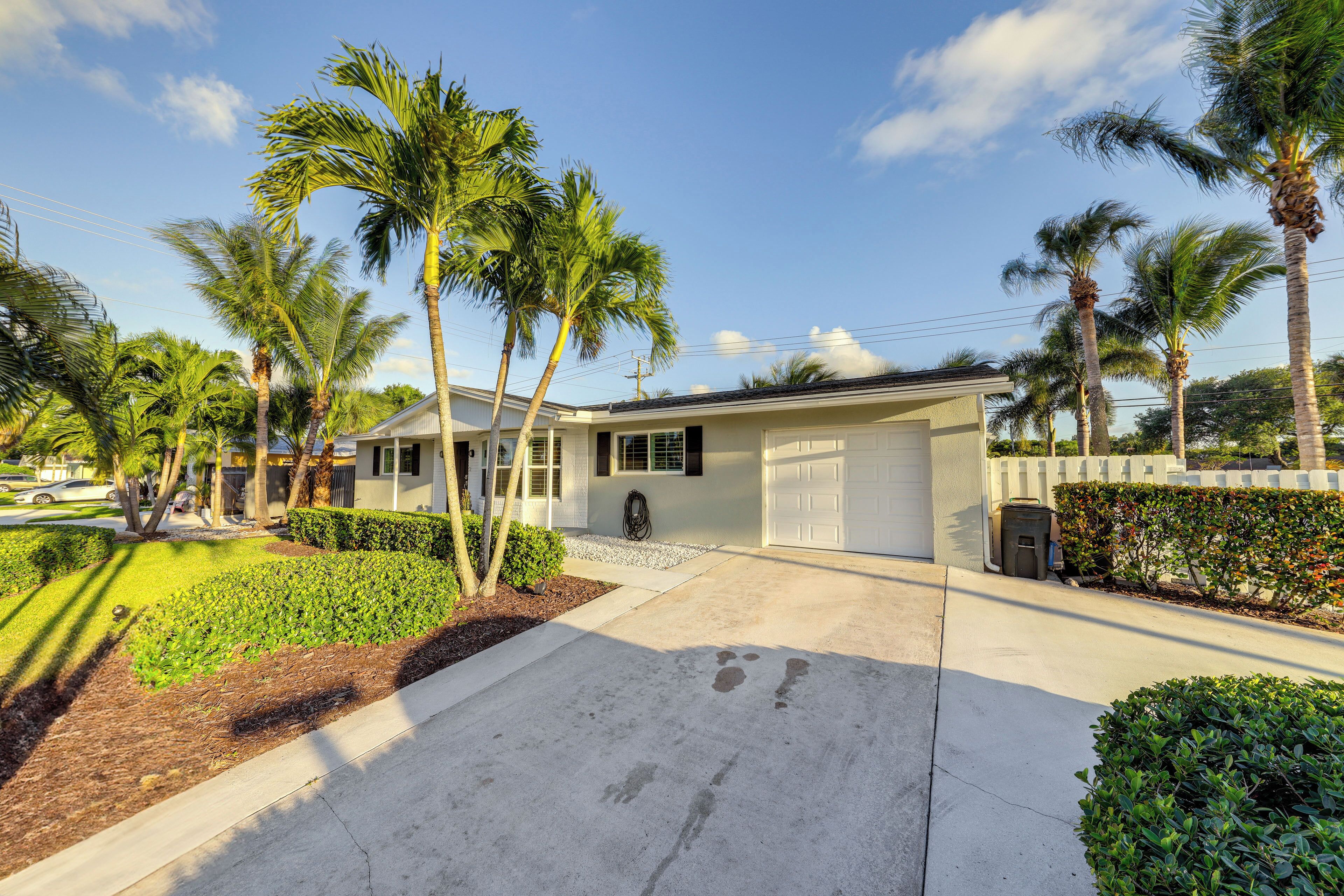 A residential house with a garage, palm trees, and a well-maintained lawn.