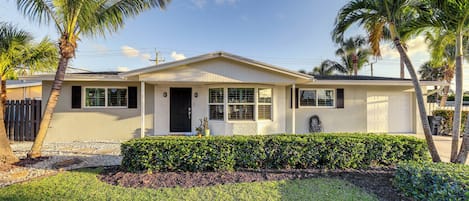 A single-story house with a front porch, palm trees, and a well-maintained lawn.
