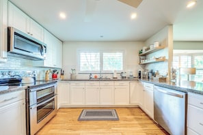 Una cocina moderna con armarios blancos, electrodomésticos de acero inoxidable y piso de madera.