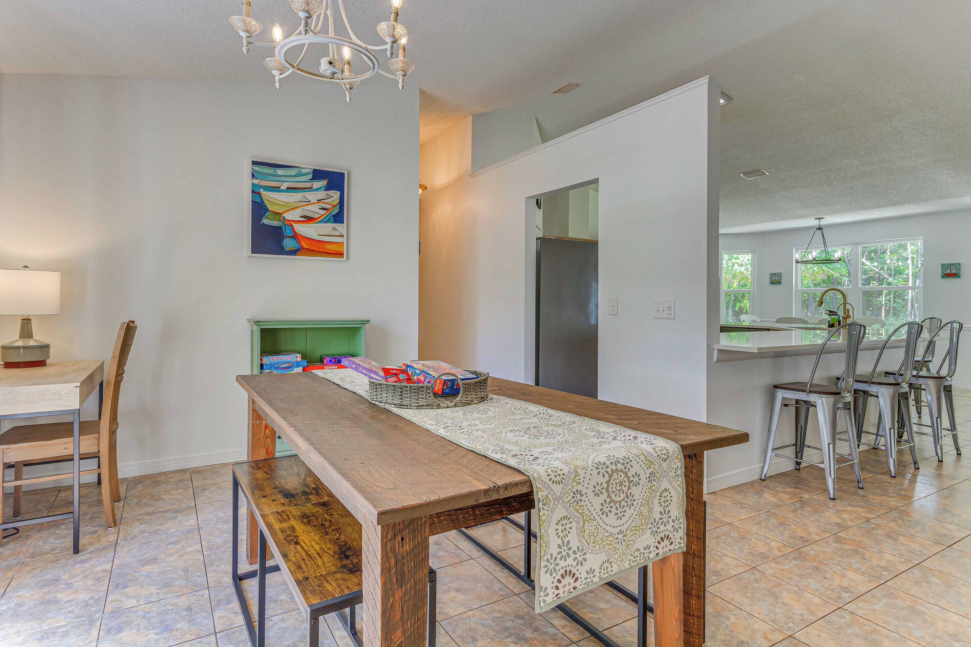 A spacious kitchen with a wooden table, chairs, and a chandelier.