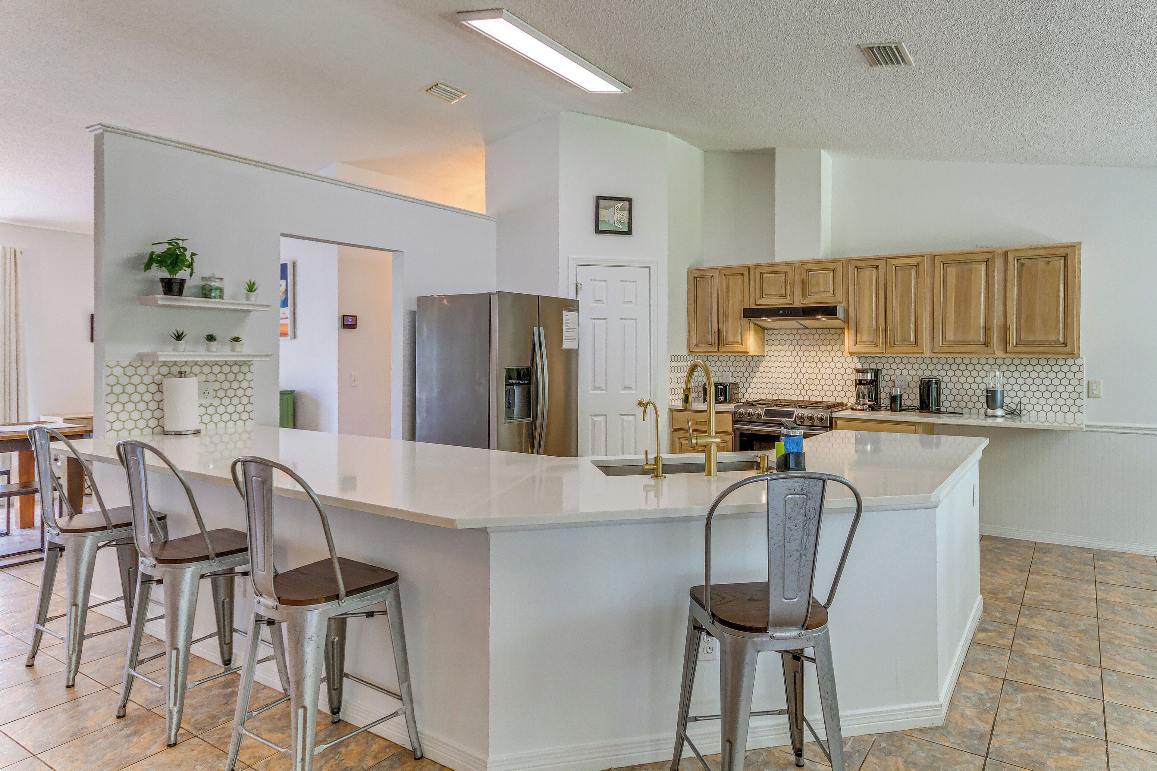 Una cocina moderna con una isla grande, taburetes de bar, armarios de madera y salpicadero de azulejos.