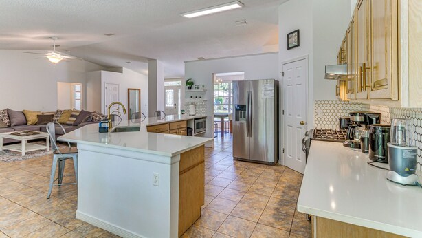A spacious kitchen with a central island, modern appliances, and a dining area with a sofa and chairs. - Pensacola Home w/ Large Yard: 4 Mi to Beach (Pensacola)