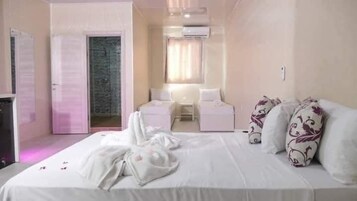Habitación de hotel con una cama grande, un escritorio y una silla. Hay una puerta que da a un baño.