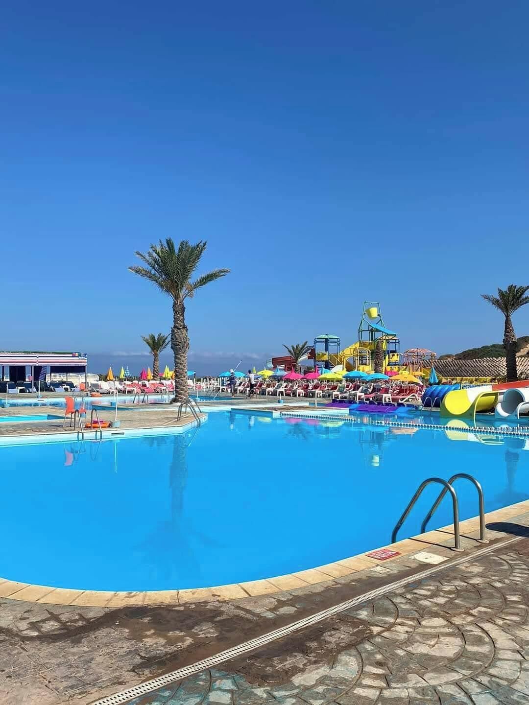 A swimming pool with a water slide and lounge chairs.