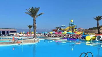 A swimming pool with a water slide and lounge chairs.