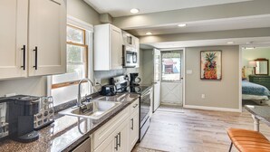 Cocina moderna con armarios blancos, encimera de granito y cafetera.