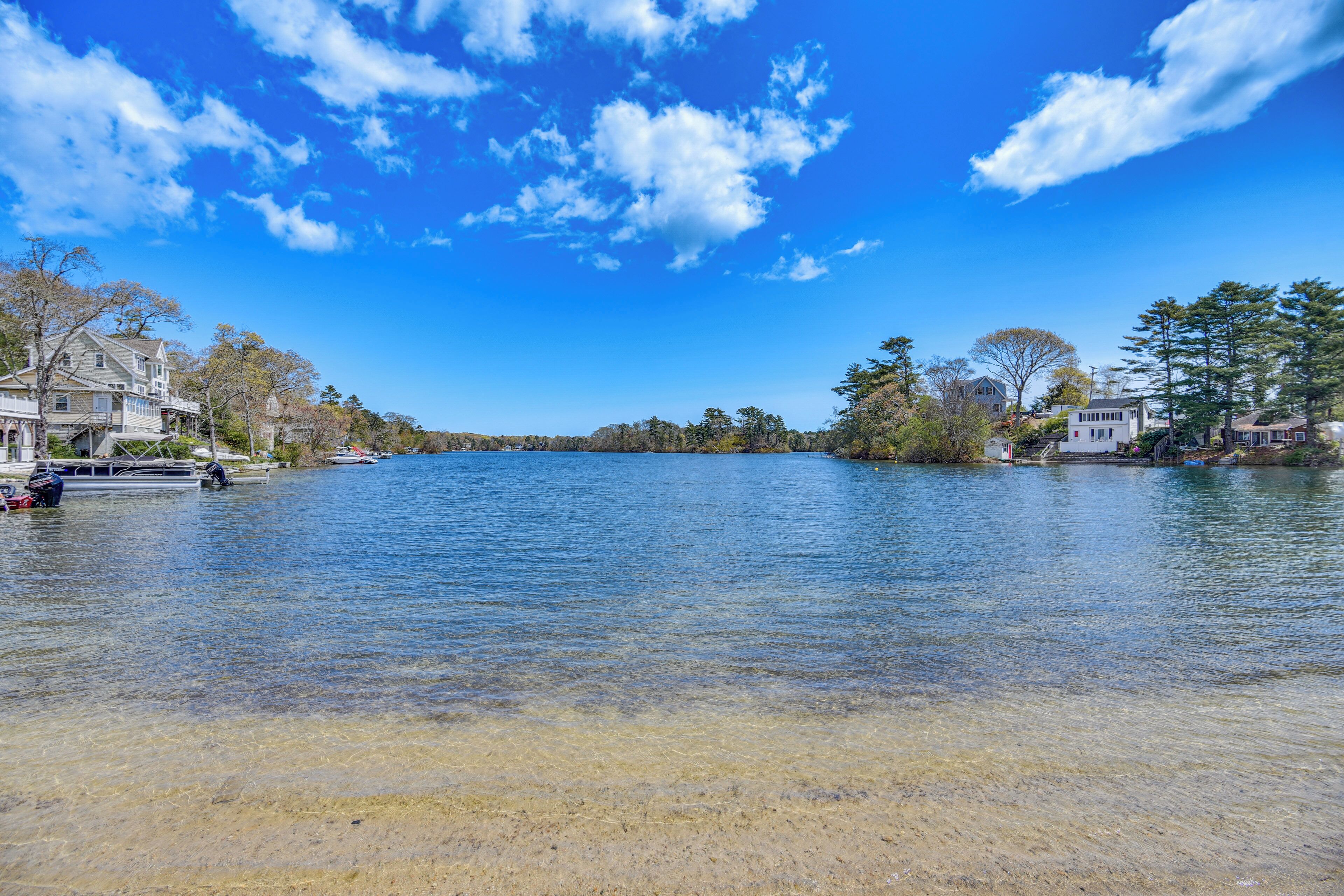 A waterfront property with a clear view of the water, boats, and houses along the shore.