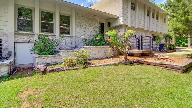 A two-story house with a stone facade, a front porch, and a well-maintained lawn.
