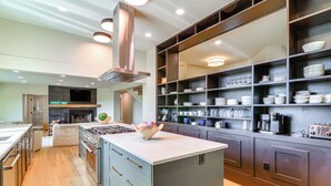 A modern kitchen with a central island, stainless steel appliances, and ample storage shelves. - Byrdstown Home on 65 Acres w/ Pool, Trail to Lake! (Allons)