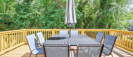 Eine Terrasse mit Tisch und Stühlen, umgeben von einem Holzwert und üppiger Bepflanzung.