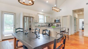 A modern kitchen with a large island, stainless steel appliances, and a dining area with a dark wooden table and chairs. - San Marcos Home w/ Fire Pit ~ 10 Mi to Downtown! (San Marcos)