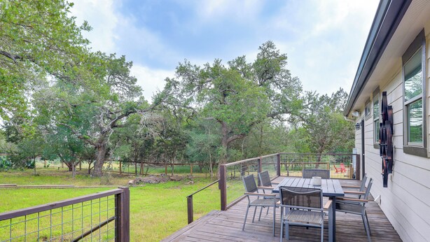 A wooden deck with outdoor furniture, surrounded by a fenced yard and trees. - San Marcos Home w/ Fire Pit ~ 10 Mi to Downtown! (San Marcos)