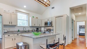 A modern kitchen with white cabinets, a granite countertop, and a central island with bar stools. - San Marcos Home w/ Fire Pit ~ 10 Mi to Downtown! (San Marcos)