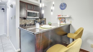 Una cocina moderna con una isla central, electrodomésticos de acero inoxidable e iluminación colgante.
