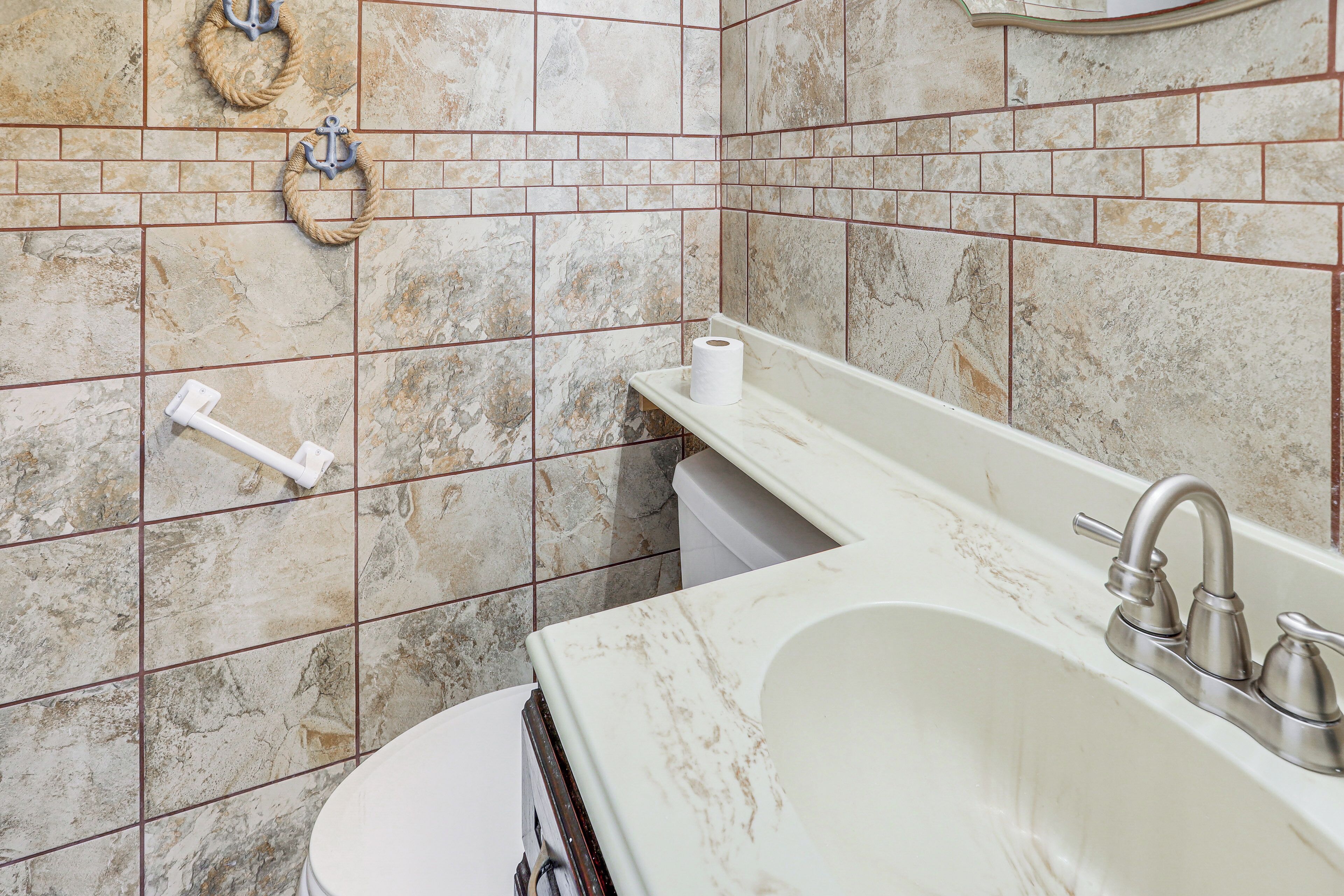 Een badkamer met een marmeren wastafel, een toilet en een handdoekhouder.