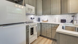 A kitchen with a white refrigerator, a microwave, a stove, and a sink. - Sarasota Duplex in Gillespie Park: 1 Mi to Dtwn! (Sarasota)