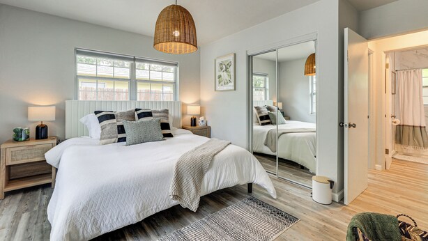 A bedroom with a large bed, bedside tables, a mirror, and a window. - Sarasota Duplex in Gillespie Park: 1 Mi to Dtwn! (Sarasota)