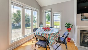 A dining area with a table set for four, large windows, a fireplace, and a view of the outdoors.