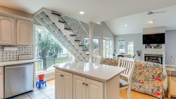 A modern kitchen with white cabinets, a built-in dishwasher, and a central island.