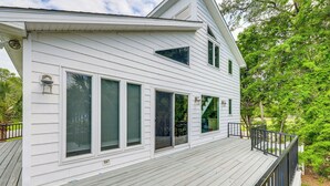 A white two-story house with a wooden deck and a black railing.