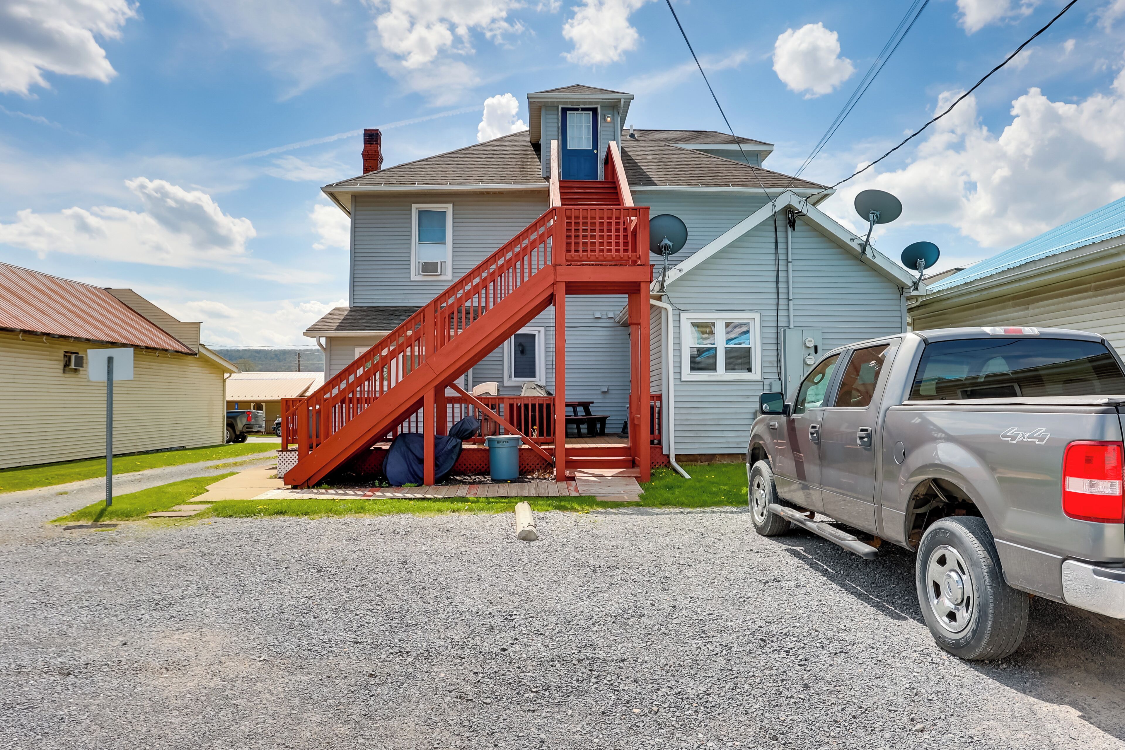 A two-story house with a red staircase, a driveway, and a parked pickup truck.