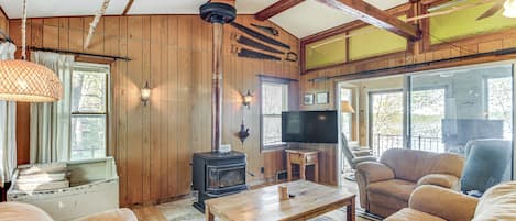 A cozy living room with wooden walls, a fireplace, a television, and comfortable seating.