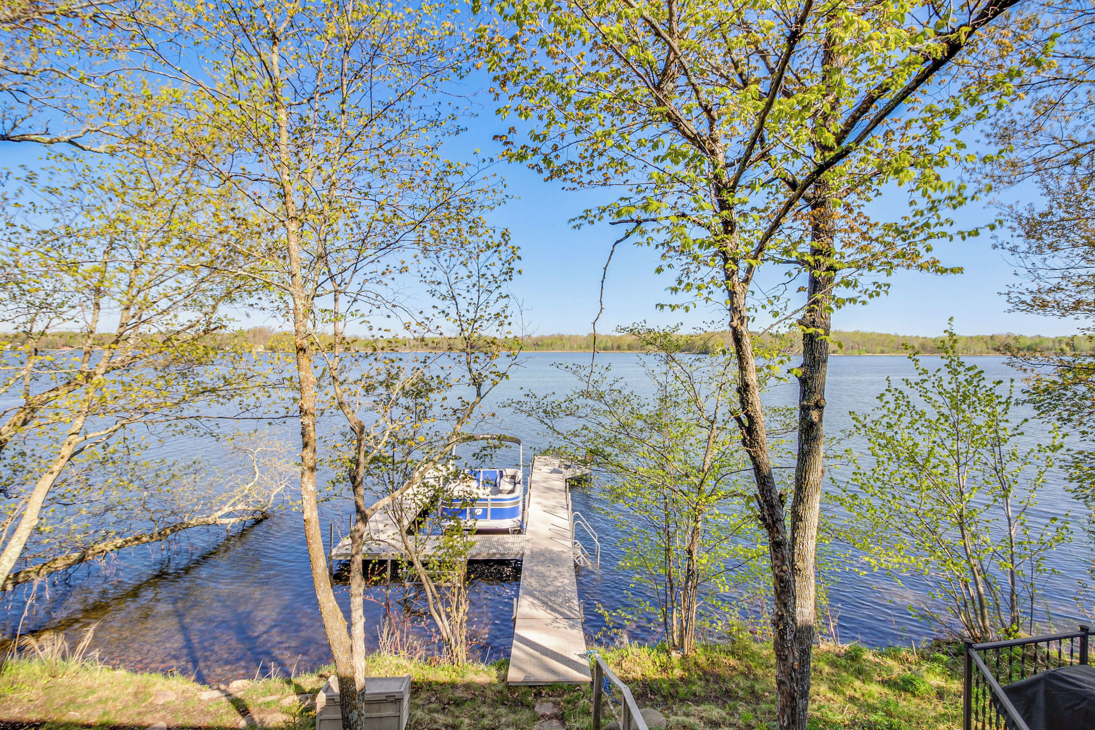 A dock extending into a lake with a boat moored at the end.