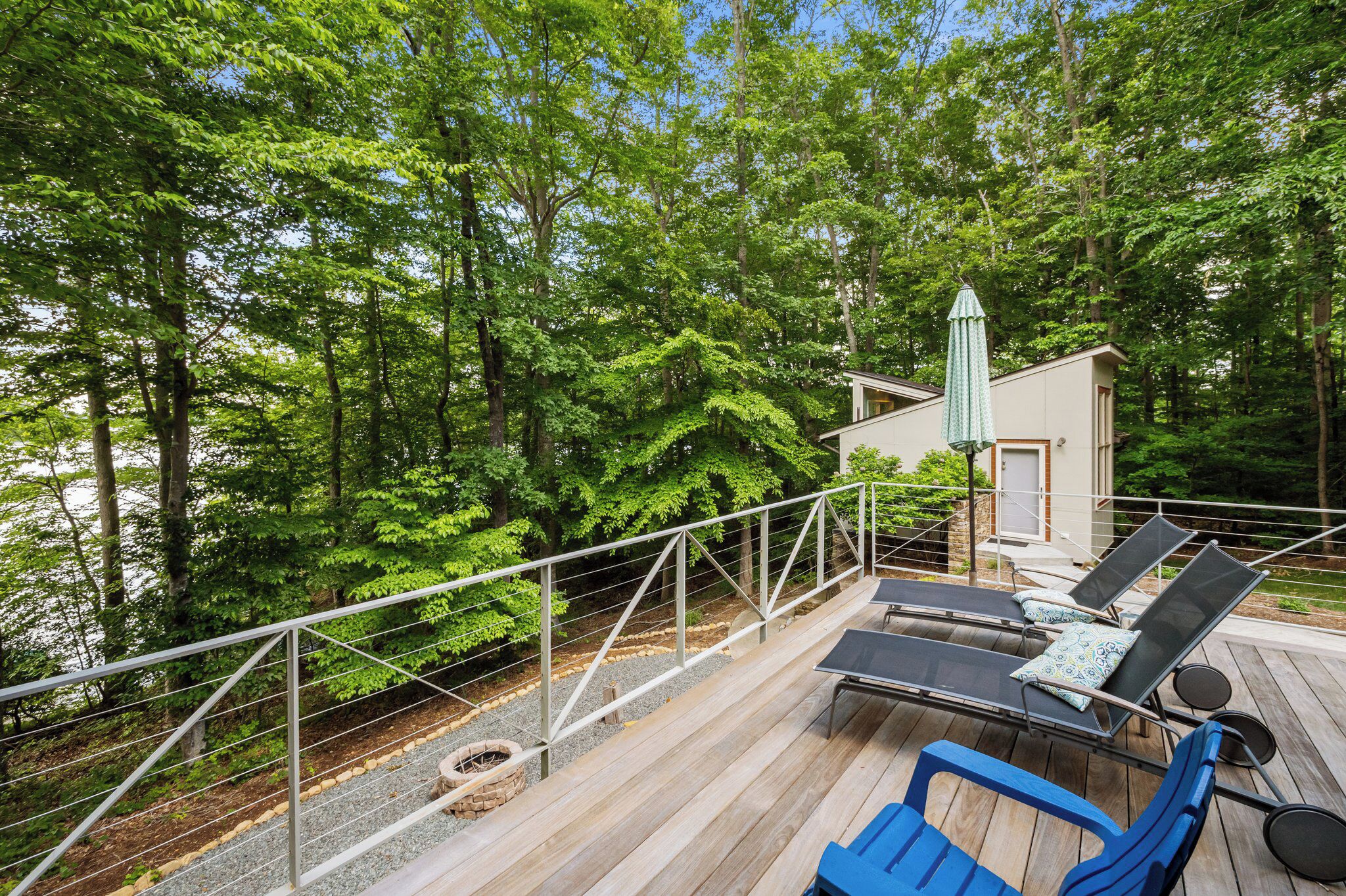 A deck with lounge chairs and a small building, surrounded by trees.