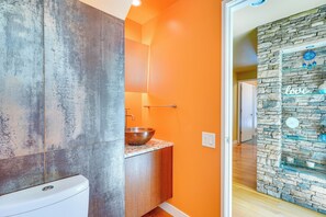 A bathroom with a stone wall, a sink with a bowl, and a mirror. - Lakefront Roxboro Home w/ Private Dock! (Roxboro)