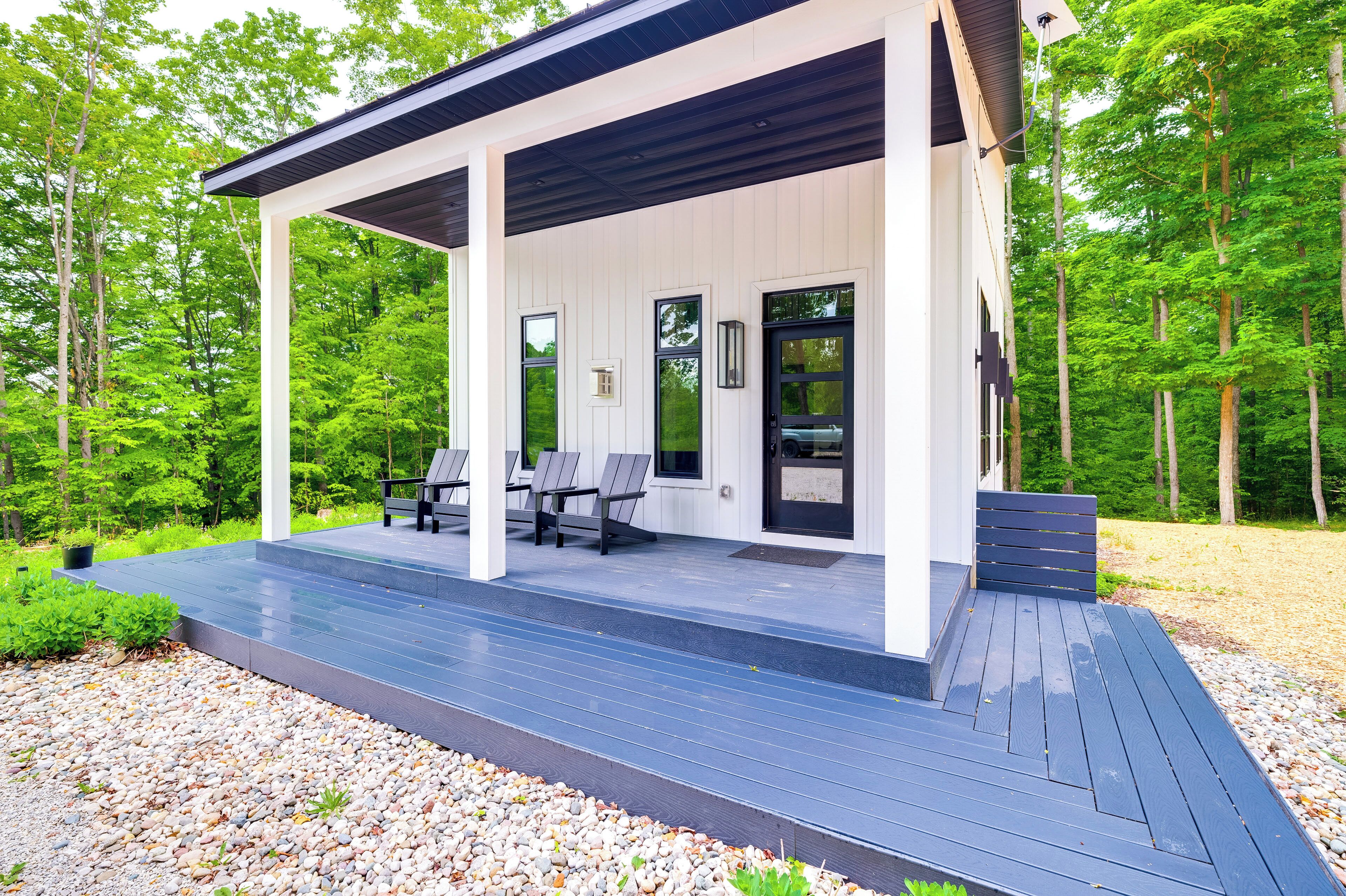 A covered outdoor area with a wooden deck, seating, and a door.