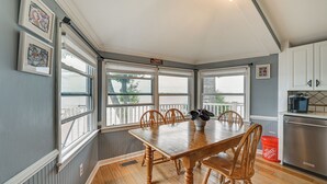 Un comedor con mesa y sillas de madera, ventanas amplias y vistas al exterior.