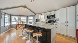 Una cocina amplia con una isla grande, muebles blancos y piso de madera.